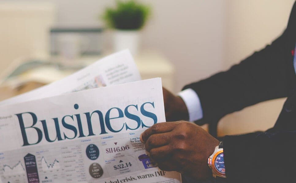 A person in a suit reading the business section of a newspaper.