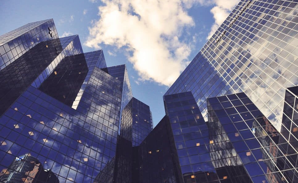 Modern skyscrapers with reflective glass facades against a blue sky with clouds.