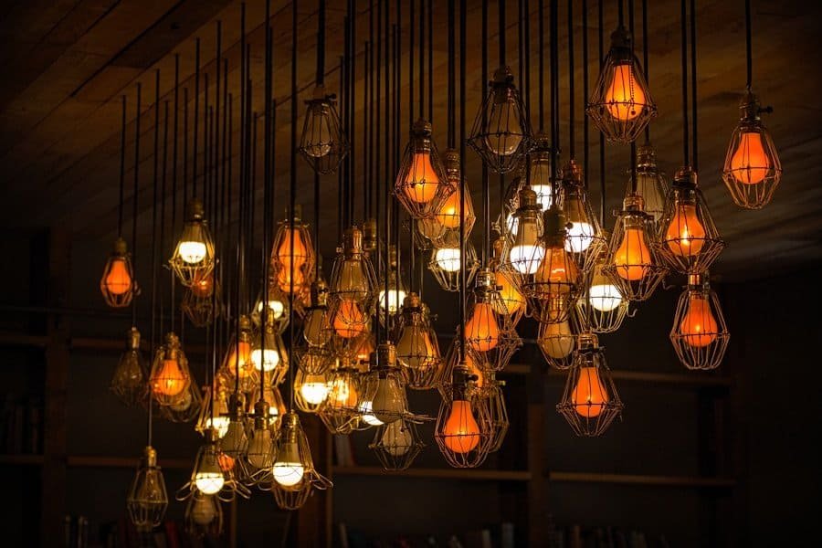 An array of vintage-style edison bulb pendant lights hanging at varying heights in a warm, dimly lit room.