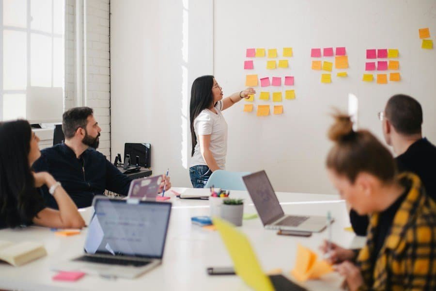 Team members in a bright office during a collaborative brainstorming session with sticky notes on the wall.