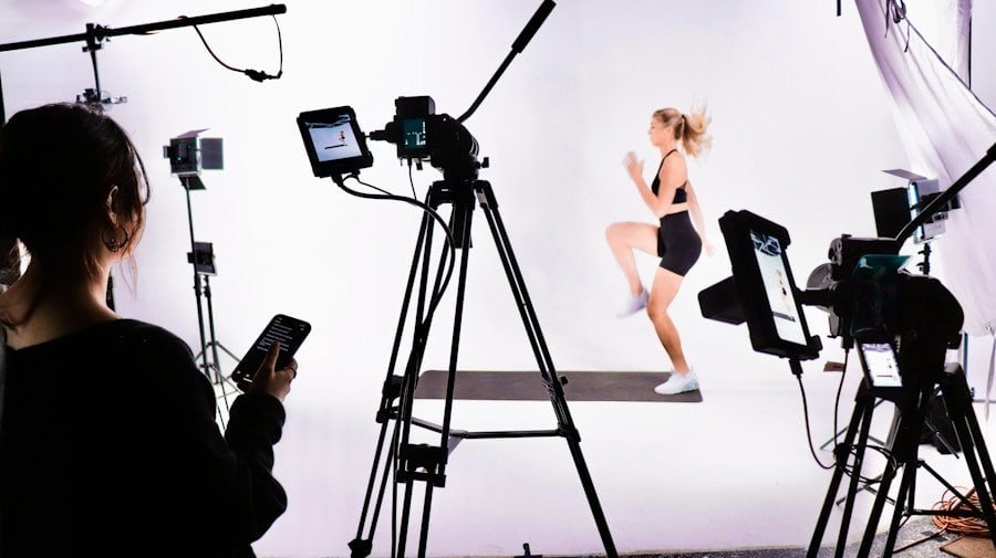 Photographer using a tablet to control a photo shoot with a model in motion, surrounded by studio lighting equipment.