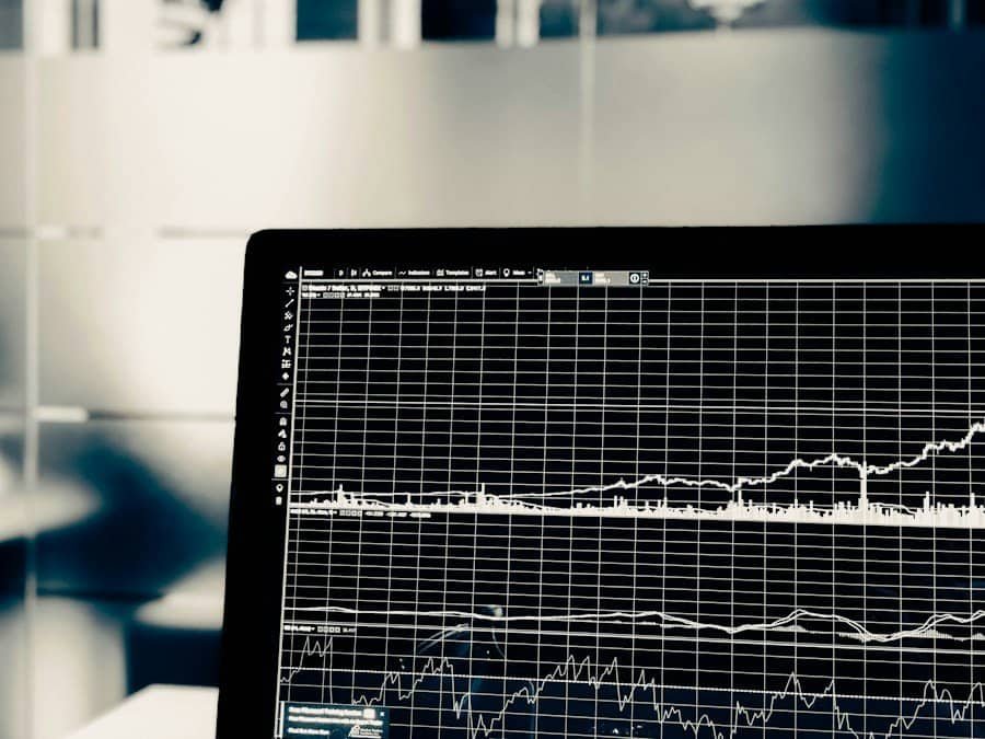 Laptop screen displaying graphs and data analysis in a monochrome office setting.