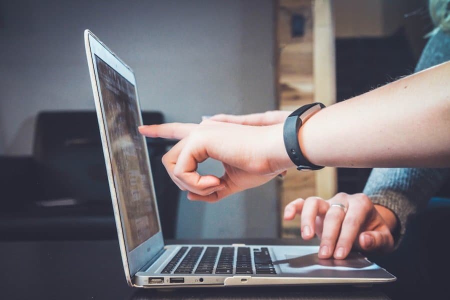 Person pointing at a laptop screen while working.