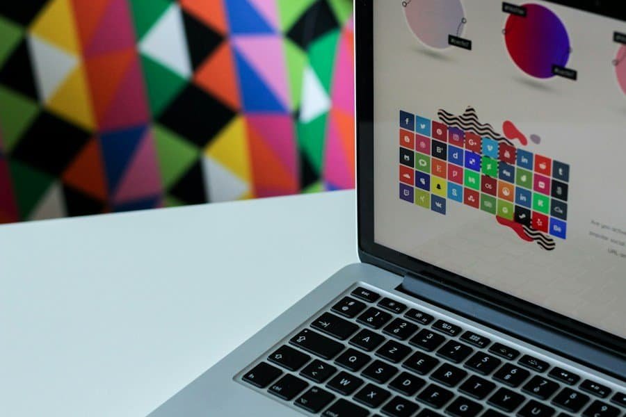 A laptop with colorful graphics on the screen, placed in front of a vibrant geometric-patterned background.